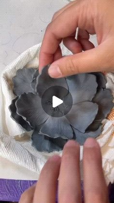 two hands are working on an object that looks like a flower