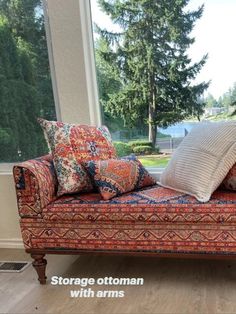 a couch sitting in front of a window with pillows on it's back end