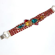 Fabulous Julianna or Julianna style bracelet that features four strands of prong set, deep red rhinestones and a front panel of multicolored, tear-drop shaped stones. The two largest stones have open backs, the rest have closed backs and are foiled. Gold tone metal, fastens securely with a fold-over clasp. Measures 7 1/4 inches long and just under 1 inch at the widest point in the front. The largest stone measures just over 5/8 of an inch by 1/2 of an inch. All the stones are present and in good Red Jeweled Bracelet For Party, Red Jubilee Bracelets For Parties, Red Jubilee Bracelet For Party, Red Crystal Rhinestone Bracelet For Party, Red Rhinestone Crystal Bracelet For Party, Red Crystal Bracelet With Rhinestones For Party, Adjustable Red Bracelet With Rhinestones, Red Rhinestone Bracelets For Party, Red Crystal Bracelets With Rhinestones