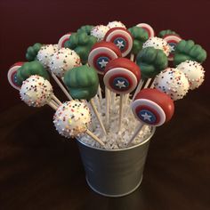 a cup filled with cake pops covered in captain america's shield and sprinkles