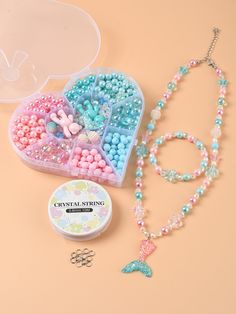 an assortment of beads and necklaces in a plastic case on a table with a cookie tin