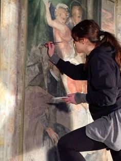 a woman is painting a mural on the wall