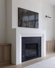 an empty living room with a fireplace and painting on the wall above it's mantle