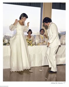 a man and woman standing in front of a table with white cloths on it