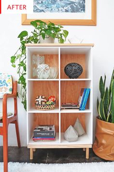 a white shelf filled with books next to a chair and potted plant on top of a rug