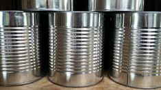 four tin canisters sitting on top of a wooden table next to each other