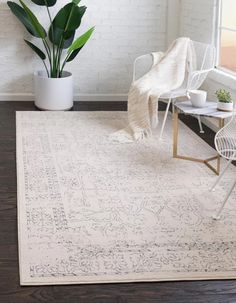 a white rug with an intricate design on it in a room next to a chair and potted plant