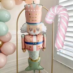 a pink and gold nutcracker statue next to balloons