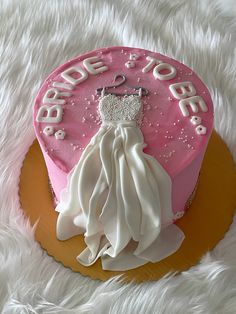 a pink cake with white frosting and a bride's dress on top