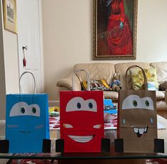 three paper bags with faces on them sitting in front of a couch and coffee table