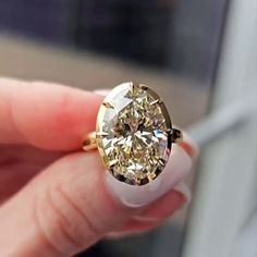 a close up of a person's hand holding a ring with a yellow diamond in it