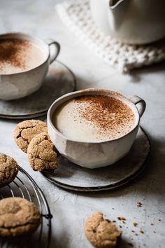 two cups of cappuccino and cookies on a table