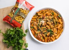 a white bowl filled with pasta and parsley next to a bag of tortellini