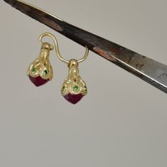 "Tiny and delicate gold dangle earrings with Six tsavorite green stones are placed on each earring and a Ruby rose cut gemstone is set in the middle. These Ruby gold drop earrings are made by a fine hand carving wax process and then cast to a 14k gold . These dainty gold earrings are oriental style, they suit a bride and any other classic look, they can be beautiful girlfriend gift. For design I am many times inspired by tree pods and try to resemble their appearance in my jewelry. When I made t Ruby Earring, Dainty Gold Earrings, Green Stones, Ruby Earrings, Ruby Jewelry, Ruby Rose, Gold Earring, Girlfriend Gift, Drop Earring