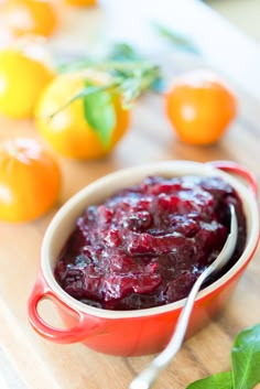 a red bowl filled with cranberry sauce on top of a wooden cutting board