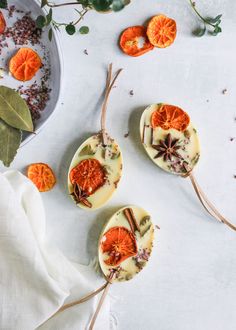 three dried oranges are sitting on a white surface next to some leaves and flowers