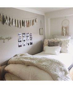 a white bed sitting in a bedroom next to a wall with pictures hanging on it