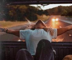 a woman sitting in the back of a truck with her arms outstretched