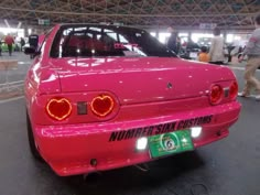 a pink car with red lights on it's hood and tail lights in the shape of hearts