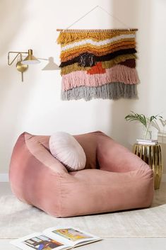 a pink bean bag chair sitting on top of a white floor next to a magazine