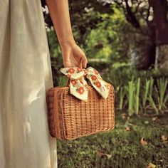 a woman is holding a wicker basket with flowers on it and her shoes are tied to the handle