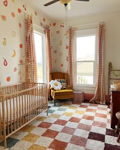 a baby's room with a crib, rocking chair and large window in it