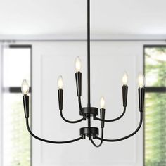 a black chandelier with five lights hanging from it's center, in front of a window