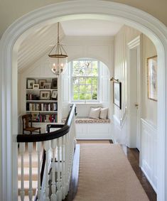 an archway leading to a living room with bookshelves and a bench in the corner