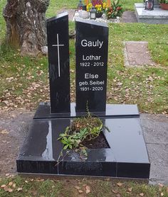 two black headstones with plants growing out of them in the ground next to each other