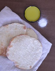 three pita breads sitting on top of a napkin next to a bowl of oil