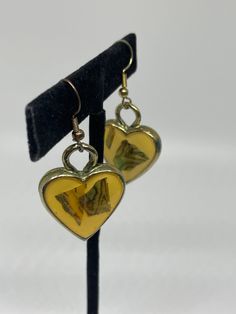 two heart shaped earrings are hanging from a stand