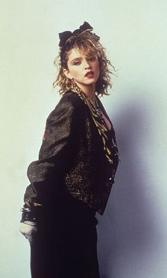 a woman with curly hair wearing a green jacket and black pants, posing for a magazine cover