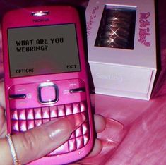 a person holding a pink cell phone in front of a box with the message what are you wearing?