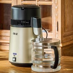 a blender sitting on top of a wooden table next to a glass container with a lid