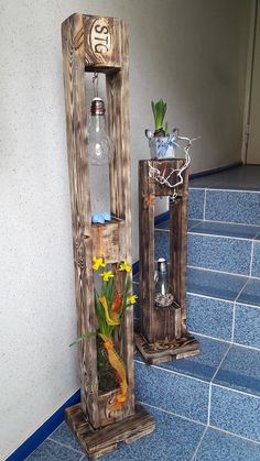 two wooden vases with plants and fish in them on blue tile floor next to wall