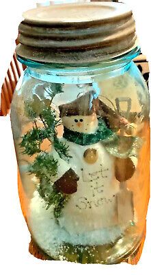 a snowman in a mason jar filled with water and other things to decorate it