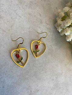 This pair of earrings is made with gold colored heart charms, gold colored earring hooks, gold colored rose charm with red and green enamel paint.  These earrings are inspired by Beauty and the Beast!  If you have any questions or concerns feel free to contact owner and designer at hannahsjeweltique@gmail.com  Visit my website at HannahsJeweltique.com Gold Enamel Earrings For Valentine's Day, Rose Gold Metal Heart Earrings For Valentine's Day, Gold Enamel Heart Charm Earrings, Gold Enamel Heart Earrings For Valentine's Day, Gold Enamel Heart Earrings, Gold Enamel Heart-shaped Earrings, Gold Heart-shaped Enamel Earrings, Gold Heart-shaped Flower Earrings As Gift, Heart-shaped Gold Flower Earrings As Gift