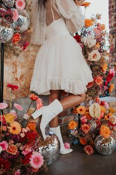 a woman in a white dress and high heeled boots is posing for the camera