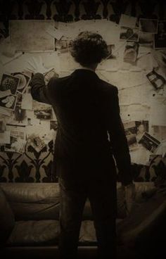 a man standing in front of a wall with pictures on it and his back to the camera