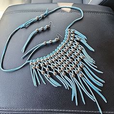 Elevate your style with this stunning boho jewelry set that exudes a unique and fashionable vibe. The set includes a beautiful blue leather macrame necklace and matching dangle earrings that feature intricate beading in silver. This is the perfect accessory for any occasion and is sure to grab attention wherever you go. The brand is known for its exceptional quality and attention to detail, making this set a must-have for any fashion enthusiast. Add this set to your jewelry collection today and Festival Macrame Dangle Jewelry, Bohemian Blue Jewelry With Adjustable Cord, Bohemian Blue Jewelry, Bohemian Fringe Choker Jewelry, Adjustable Fringe Jewelry For Festivals, Bohemian Fringe Choker Necklace, Festival Macrame Jewelry, Adjustable Fringe Choker, Silver Macrame Jewelry