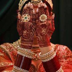 a woman with her hands covered in hendi and jewelry, showing the intricate designs on her hands