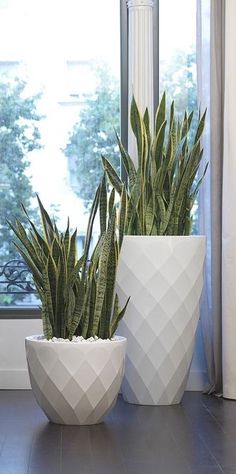 two white planters sitting next to each other in front of a window