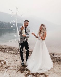 a bride and groom are throwing confetti at each other on the lake shore