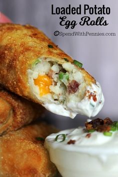 an egg roll is being held up to the camera with a fork and some sour cream on top