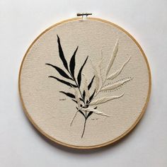 an embroidery project with black and white leaves on it's back side, in the shape of a bamboo plant