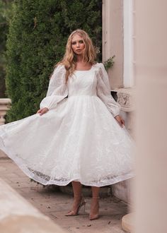 a woman in a white dress is standing outside