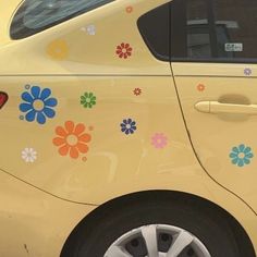 a yellow car with colorful flowers painted on the side