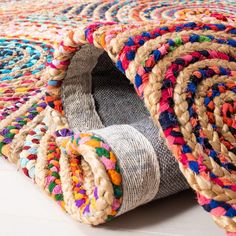 a multicolored rug is laying on the floor next to a roll of rope