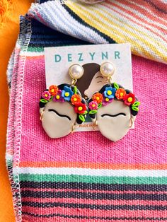 a pair of earrings sitting on top of a colorful blanket