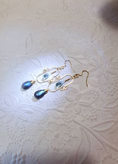 "Original Blue Topaz Labradorite, 14K Gold Filled Earrings. The Labradorite and Blue Topaz are a lovely complement to each other. Uniquely created of Gold Filled Wires, Handmade wire wrapped gemstones, and hammered in my home studio in Florida. 14K Gold Filled Wire is Nickle Free.2 5/8\" inches long by 7/8\" inches wide. These earrings have classic lines and are perfect for day wear or a special evening out. These earrings come with soft silicone earring backs. These Beautiful handmade pair of e Blue Briolette Wire Wrapped Earrings, Blue Briolette Earrings For Wedding, Blue Gemstone Chandelier Earrings For Gifts, Wire Wrapped Briolette Earrings For Anniversary, Wrapped Gemstones, Jewelry Gold Earrings, Green Amethyst Earrings, Labradorite Earrings, Blue Topaz Earrings